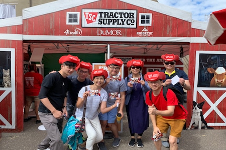 An image of a group of people wearing branded red cowboy hats in front of a Tractor Supply Co pop up display for brand awareness.